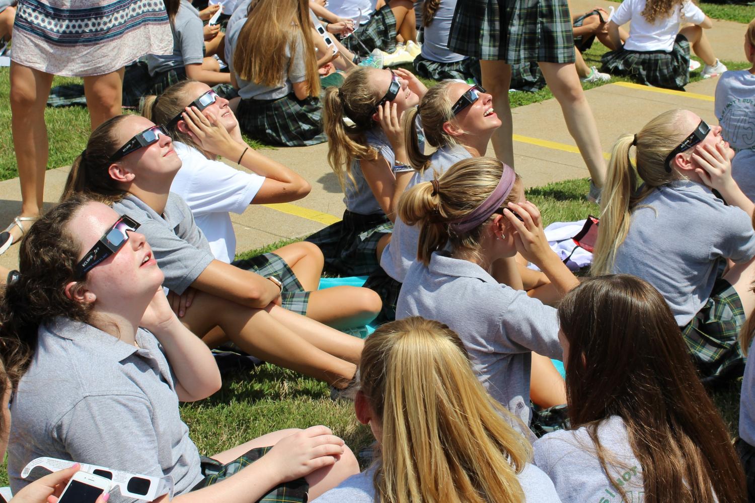 Students sit on the lawn and enjoy the eclipse.