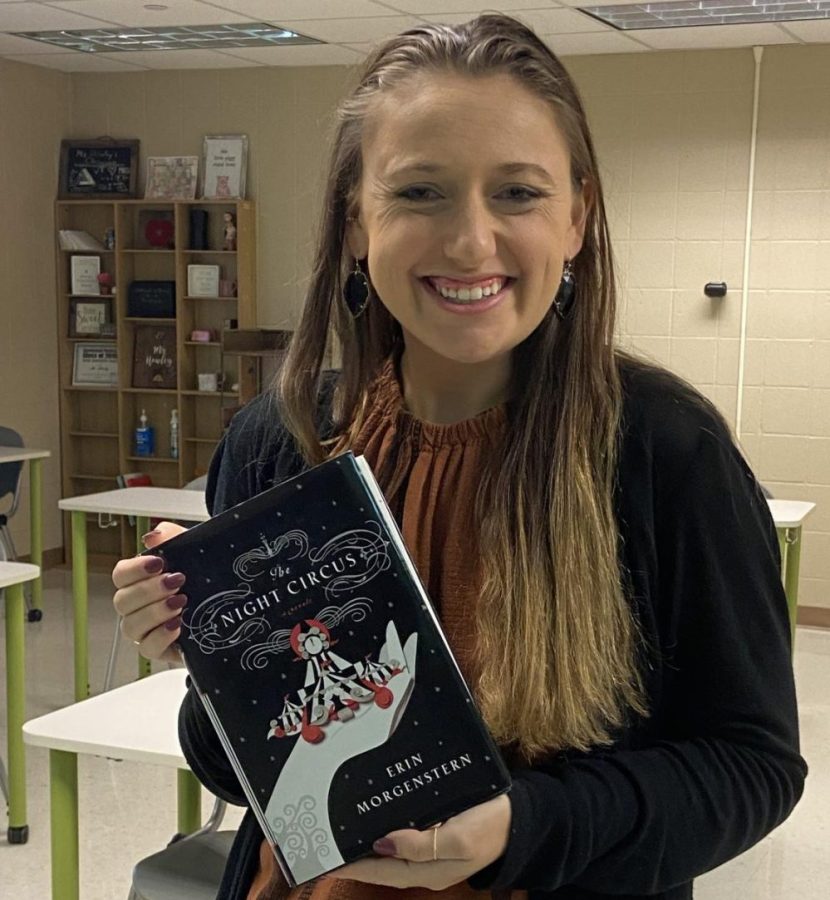 Math teacher Ms. Howely holding The Night Circus by Erin Morgenstern. 