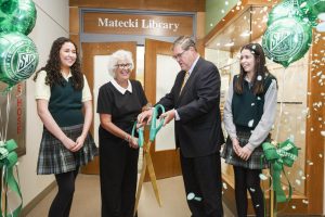 Mrs. Kathleen Matecki 74 and her husband Paul cut the ribbon for the opening of the new Matecki Library as their nieces senior Maria Mueller and sophomore Carolyn Mueller watch.