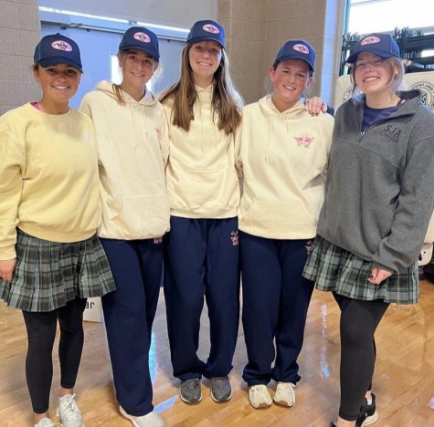 Seniors, (from left to right) Annie Mortland, Clare Barry, Sarah Gillmore, Jane Mortland, and Brynley Wall, pose to show the 2022 Mission Week sweatpants, sweatshirts, and hats. 