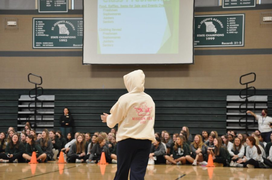 A senior class officer showcases the senior classs sweatshirt and sweatpants during the Mission Week Kickoff.
