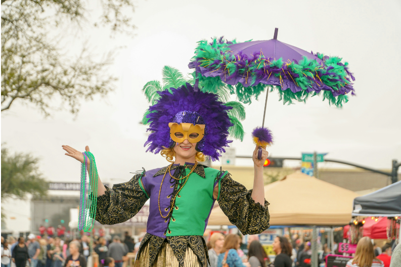 A lady celebrates Mardi Gras by wearing traditional purple, green, and gold clothing for a parade.