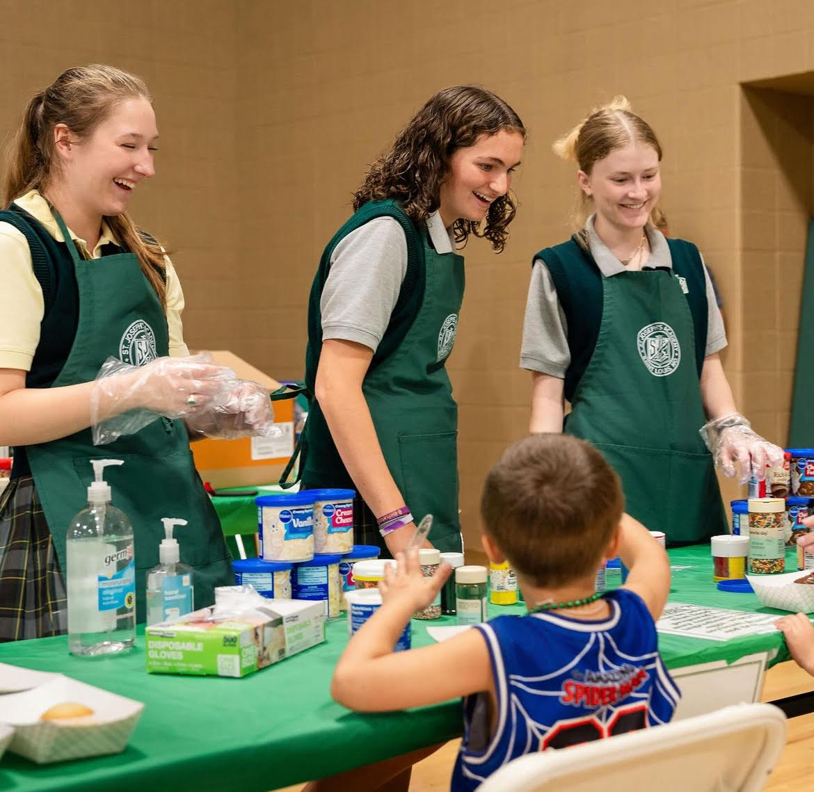 Madelyne Voss '25, Grace Laffey '27, and Catherine Martin '25 volunteer at the cupcake decorating station during Angel Fest.